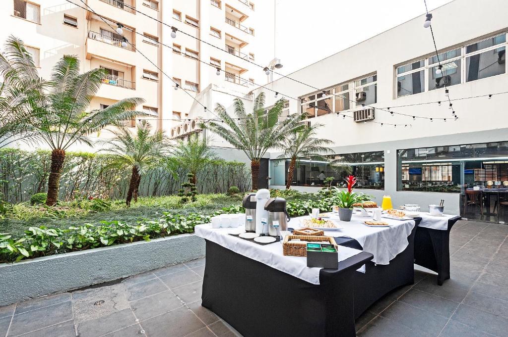 Área aberta do Slim São Paulo Congonhas by Slaviero Hotéis com um jardim e algumas mesas com bebidas e pães
