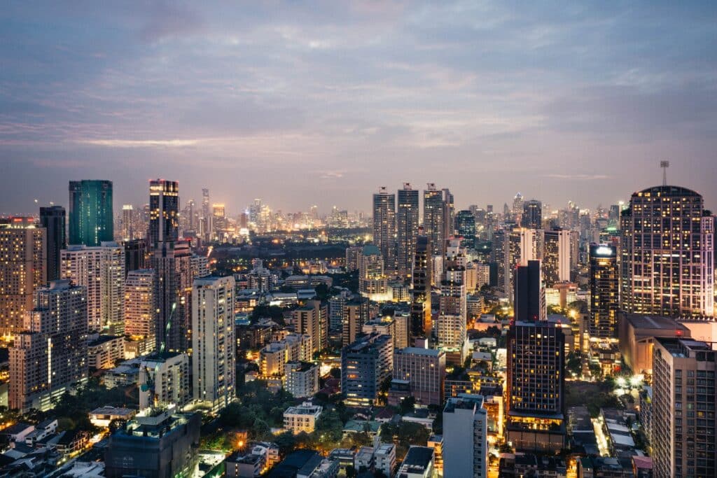 Visão aérea de um centro de Bangkok com muitos prédios e arranha céus supermodernos e iluminados em um dia com muitas nuvens no céu para representar o seguro viagem Bangkok.