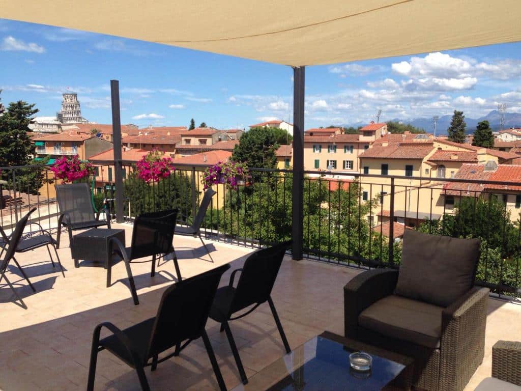 terraço do Hotel Di Stefano, um dos hotéis em Pisa, com várias cadeiras e mesinhas baixas com vista da cidade e da torre ao fundo