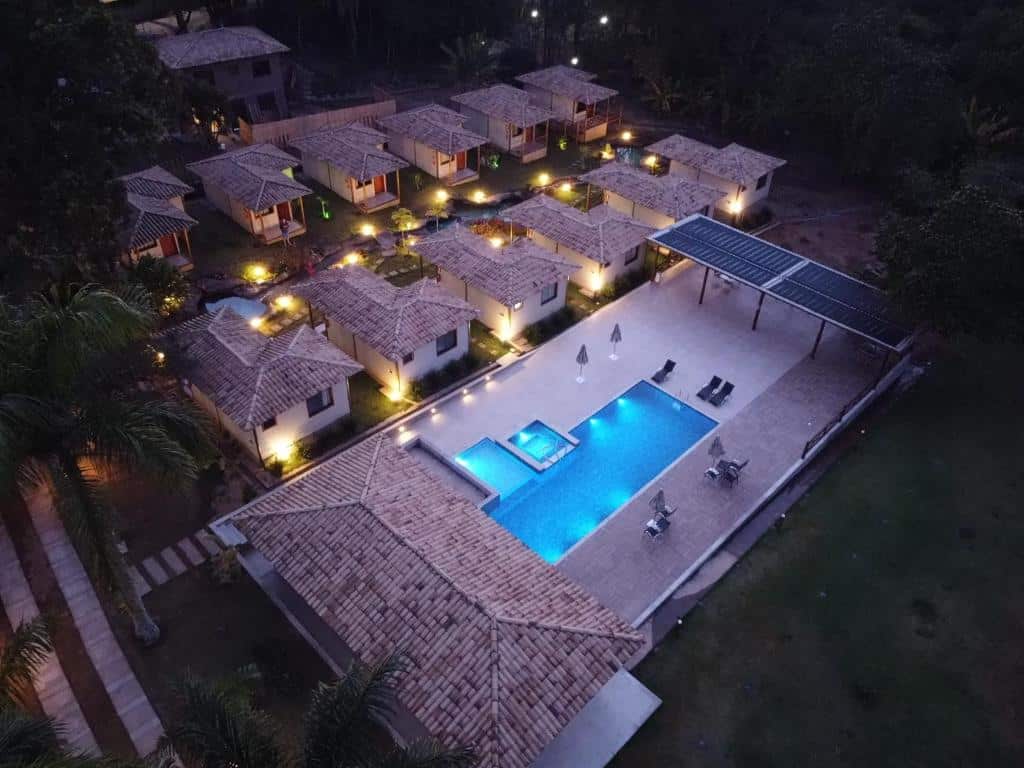 vista de cima da Pousada Villa Recanto dos Lagos, um das pousadas em Brumadinho, com piscina retangular e vários chalés iguais com luzinhas acesas, porque está de noite