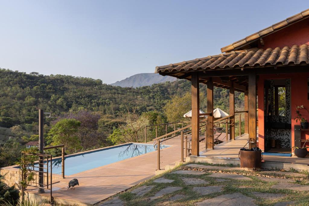vista da serra da Villa Severina, uma das pousadas em Brumadinho, com a entrada de um lado com detalhes em madeira e do outro, uma piscina retangular comprida que dá vista para a vegetação e a serra