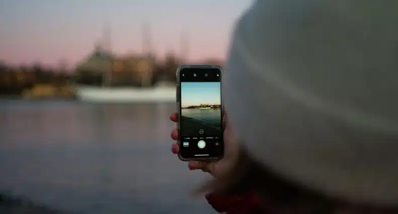 pessoa de costas com uma toca segurando um celular que dá vista para a baía da cidade, que ilustra o post de chip celular Estocolmo