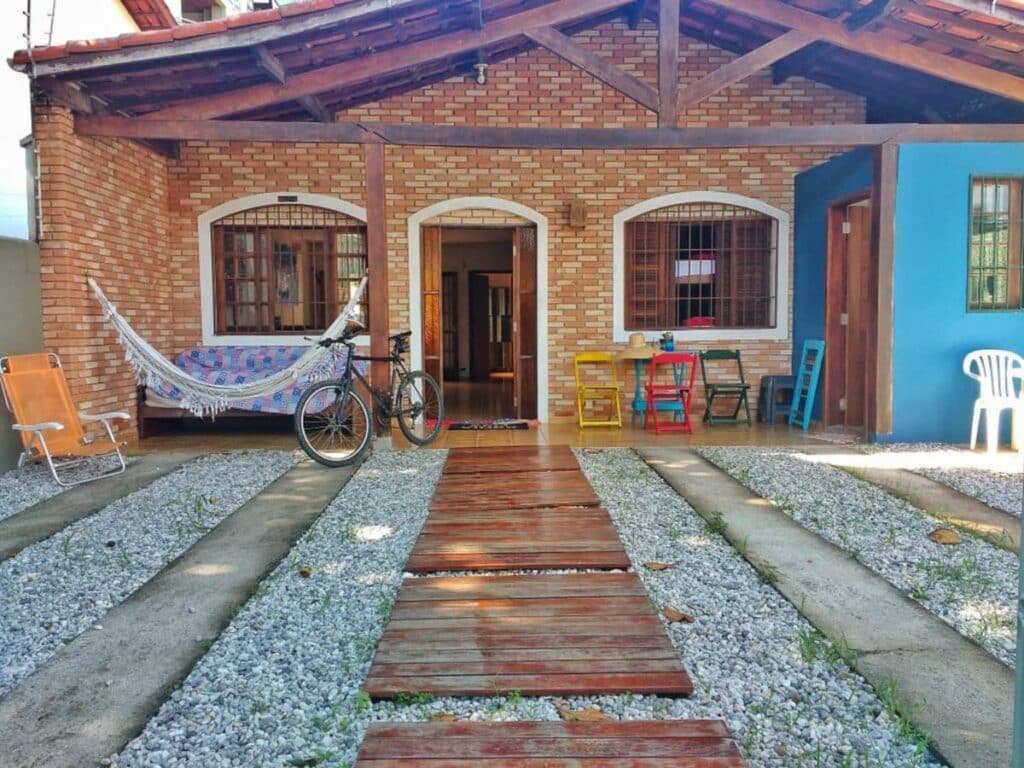Casa do Wanderlust Guest House com uma varanda na frente com mesas e cadeiras coloridas, uma rede, um sofá e uma bicicleta