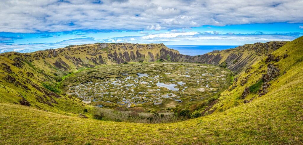 vista de uma cratera bem arborizada com água em Rano Kau, Hanga Roa com céu azul e muitas nuvens, para ilustrar o post de chip celular Ilha de Páscoa