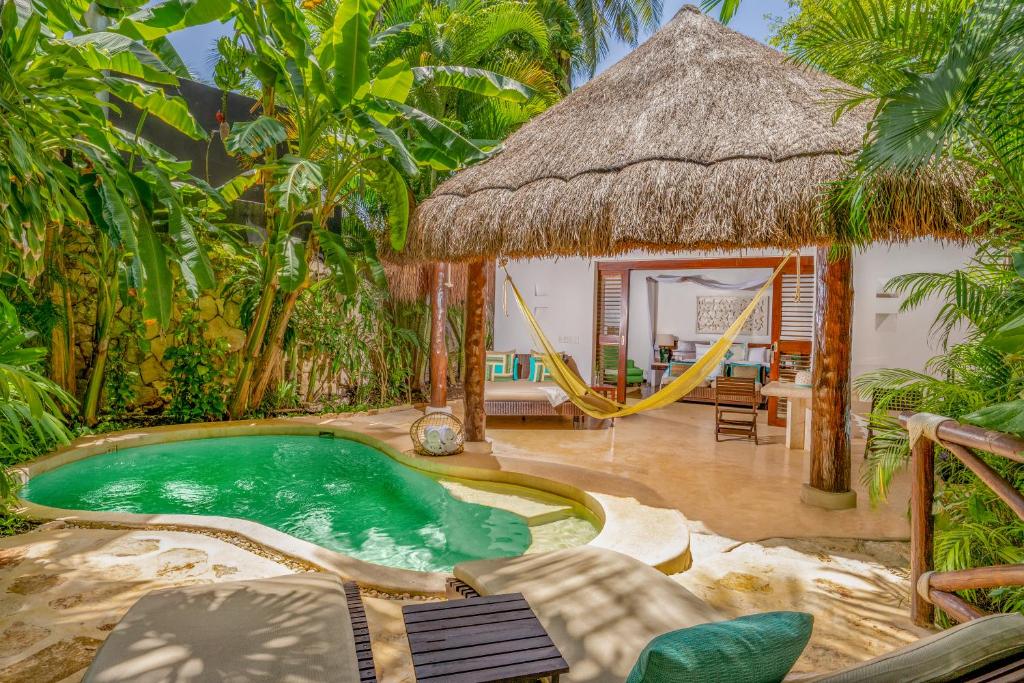 Quarto no Viceroy Riviera Maya - Luxury Resort com piscina privativa, há um pequeno deck ao redor com coqueiros e duas espreguiçadeiras, mais ao lado uma varanda ampla que leva até o quarto