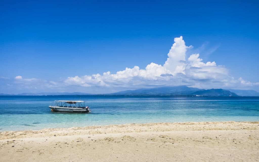 vista de um barco na praia da Ilha Viti Levu, com areias brancas e águas azuis cristalinas, com céu muito azul com nuvens, para ilustrar o texto de chip celular Fiji