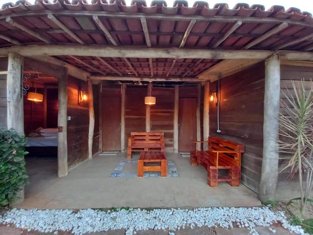 Área de estar rústica do La Villa Chalés Garden com bancos de madeiras e uma mesa de centro. Representa Chalés em Serra Negra.
