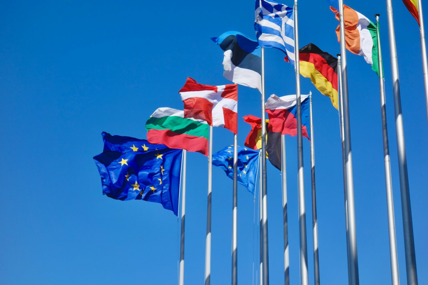 Bandeiras da UE e de países europeus no Parlamento Europeu, na cidade de Strasbourg, na França, em um dia de céu azul intenso e sem nuvens, ilustrando o post sobre o ETIAS