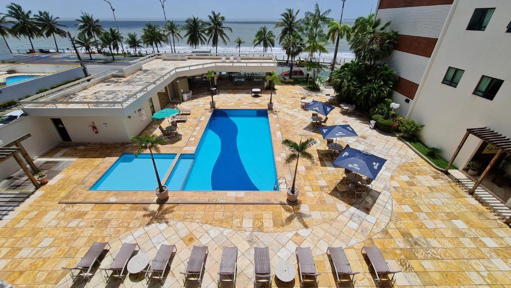 Piscina do Brisamar Hotel & SPA São Luís com um deck bem extenso ao redor com espreguiçadeiras, logo após a piscina há uma avenida e é possível já ver o mar