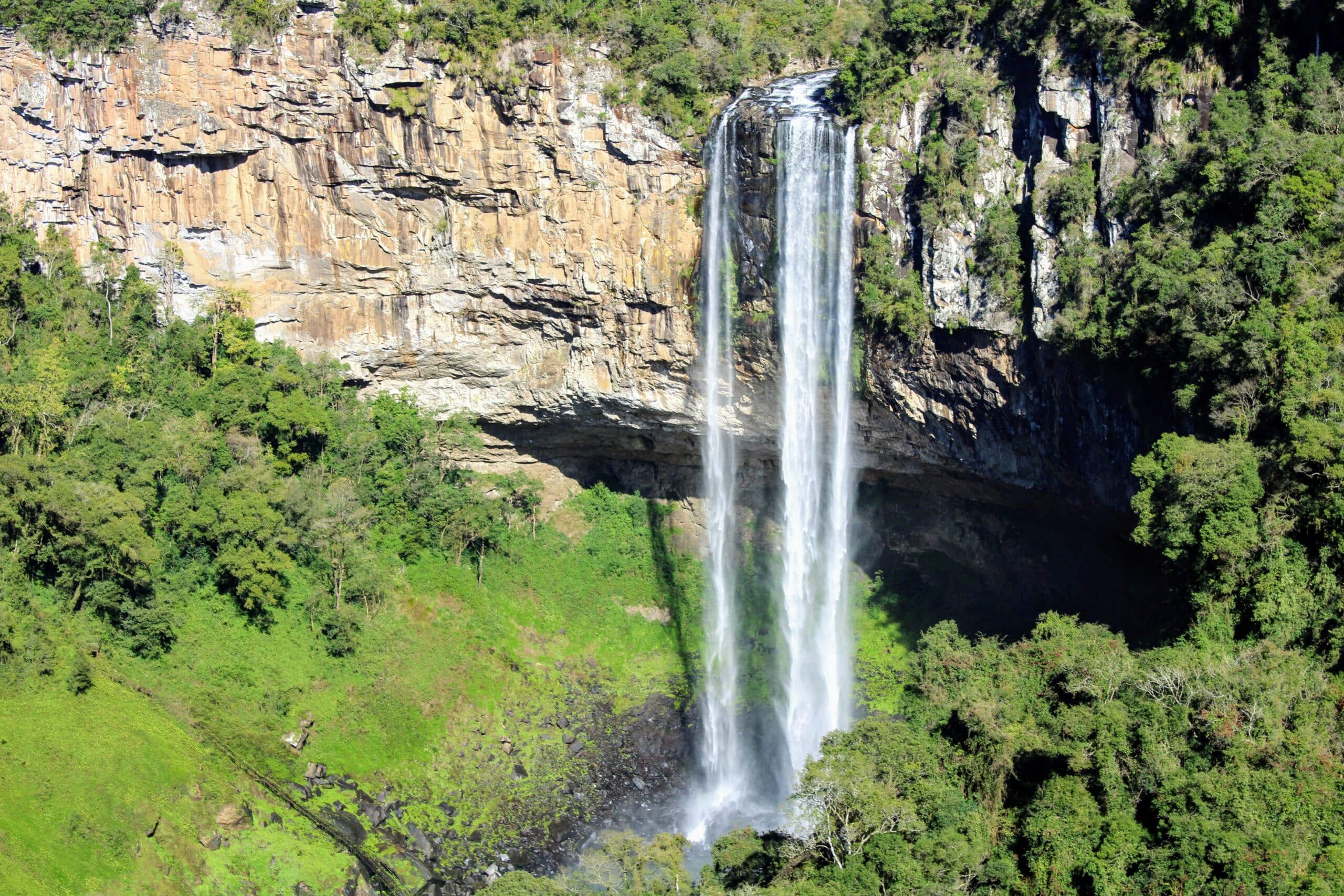 Vista de cima da Cascata do Caracol, em Canela, no Rio Grande do Sul, com uma queda de cachoeira enorme em meio a vegetação local.