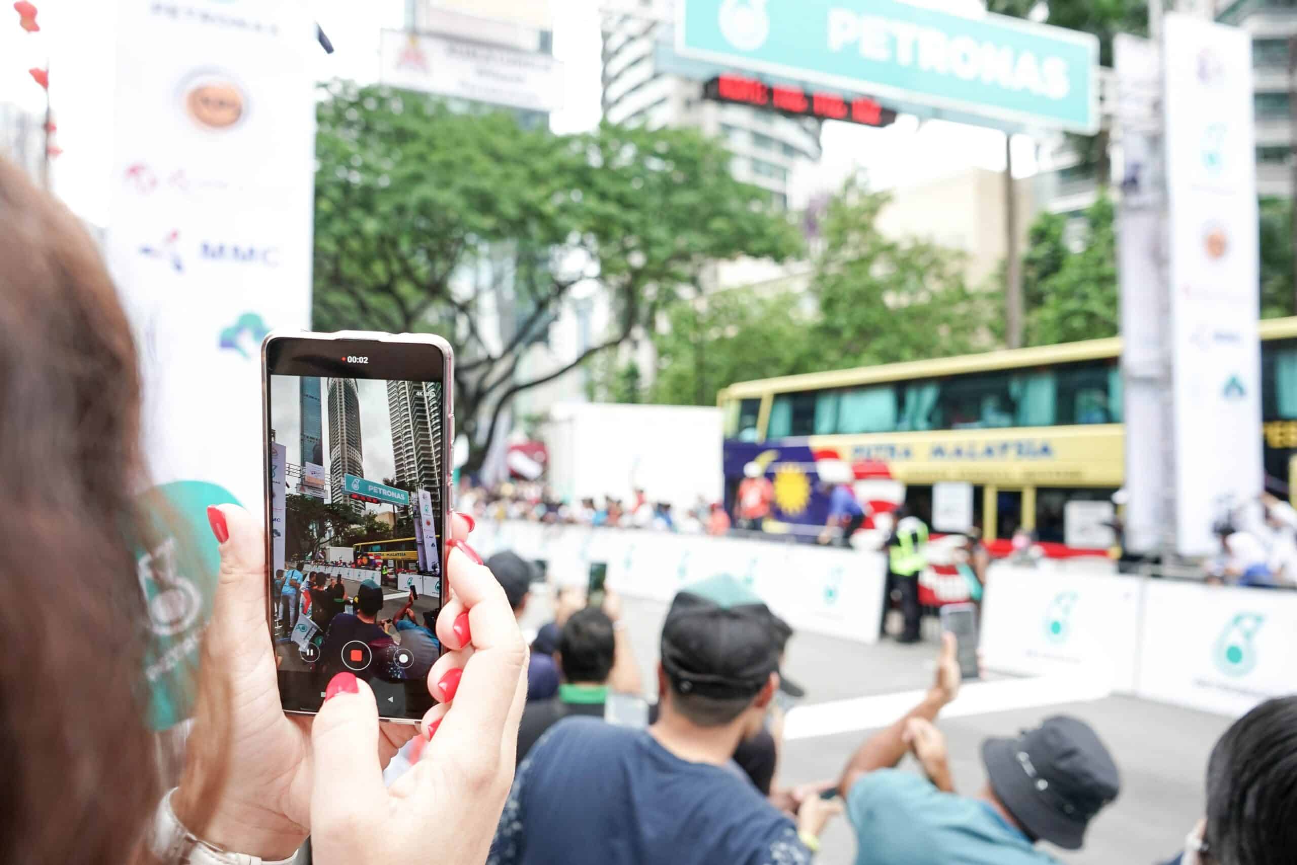 Mulher tirando foto durante o dia na ruas de Jalan Ampang, Kuala Lumpur, Malásia. Representa chip celular Malásia.