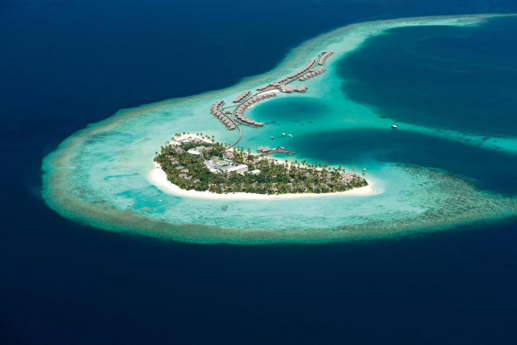 Ilha isolada onde fica o Constance Halaveli, um dos hotéis em Maldivas, com mar azul escuro e nas proximidades da costa da ilha o mar é mais claro, numa tonalidade cristalina. Há alguns bangalos flutuantes no mar