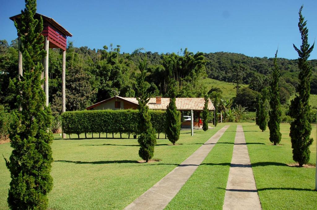 Vista da entrada do Chalé Lufre durante o dia, com gramas verdes e árvores na porta da entrada e ao fundo o chalé. Representa chalés em Santo Antônio do Pinhal