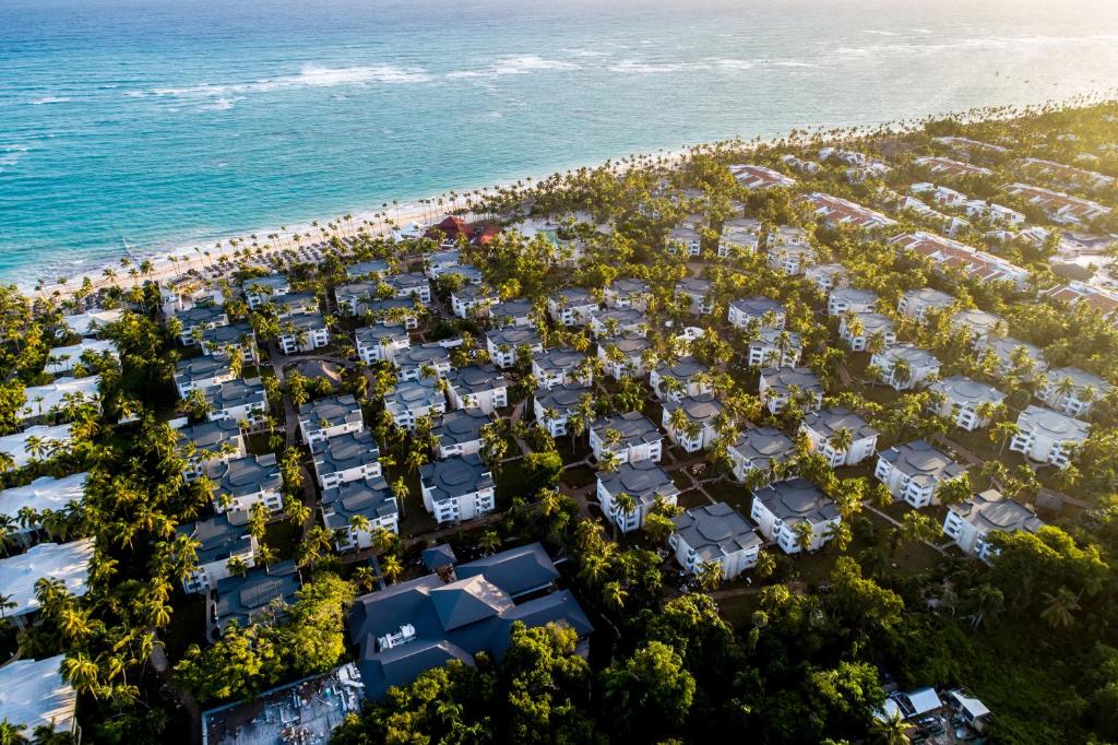 Vários prédios espalhados com árvores espalhadas em volta, em uma área beira-mar, com areia branca e mar azulado. Imagem para ilustrar o post como escolher um resort em Punta Cana
