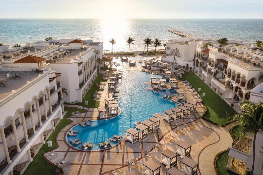 Vista aérea do Hilton Playa del Carmen, an All-Inclusive Adult Only Resort com uma piscina dominando o centro da propriedade que oferece vista direta para o mar