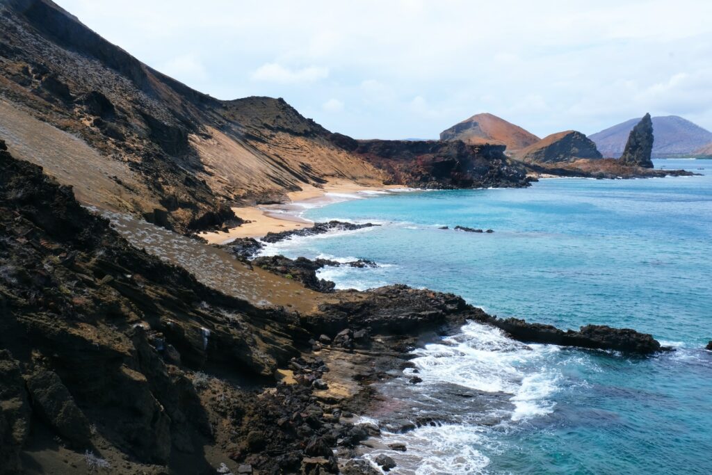 baía rochosa e sinuosa na Ilha Bartolomé com uma praia de águas azuis claras e céu aberto, para ilustrar o post de chip celular Galápagos