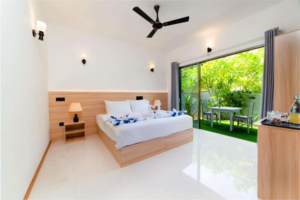 Quarto do La Palma Villa, de 15 m², com uma cama de casal; há também uma varanda com uma mesa e duas cadeiras, sendo o chão um gramado verde e com natureza em volta