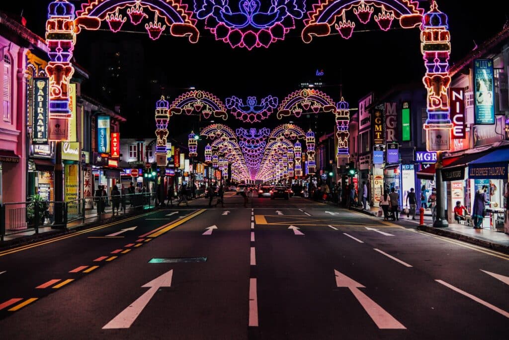 Rua com lojas e decorações indianas iluminadas com luz neon de diversas cores. É uma rua no bairro Little India, uma das recomendações de onde ficar em Singapura. - Foto: Singapore Stock Photos via Unsplash