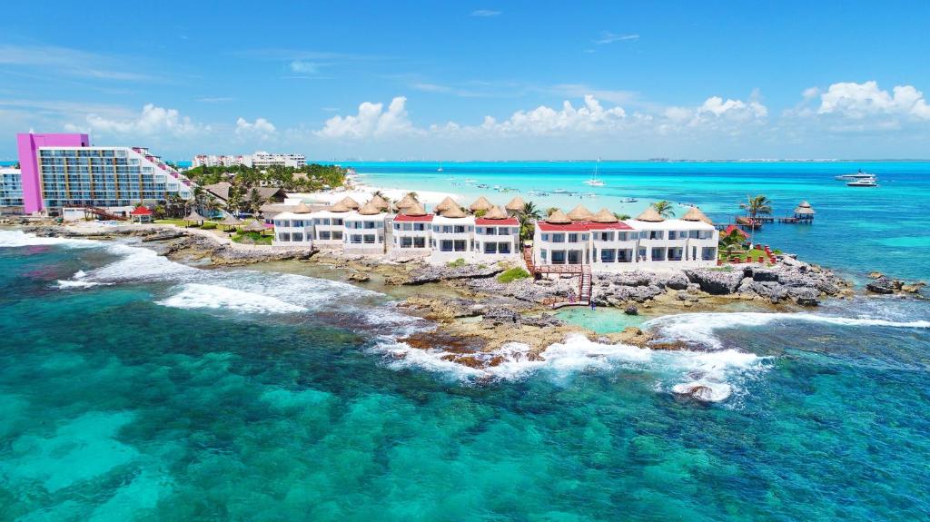 Propriedade do Mia Reef Isla Mujeres Cancun All Inclusive Resort em uma ponta da ilha cercado por pedras e um mar verde claro