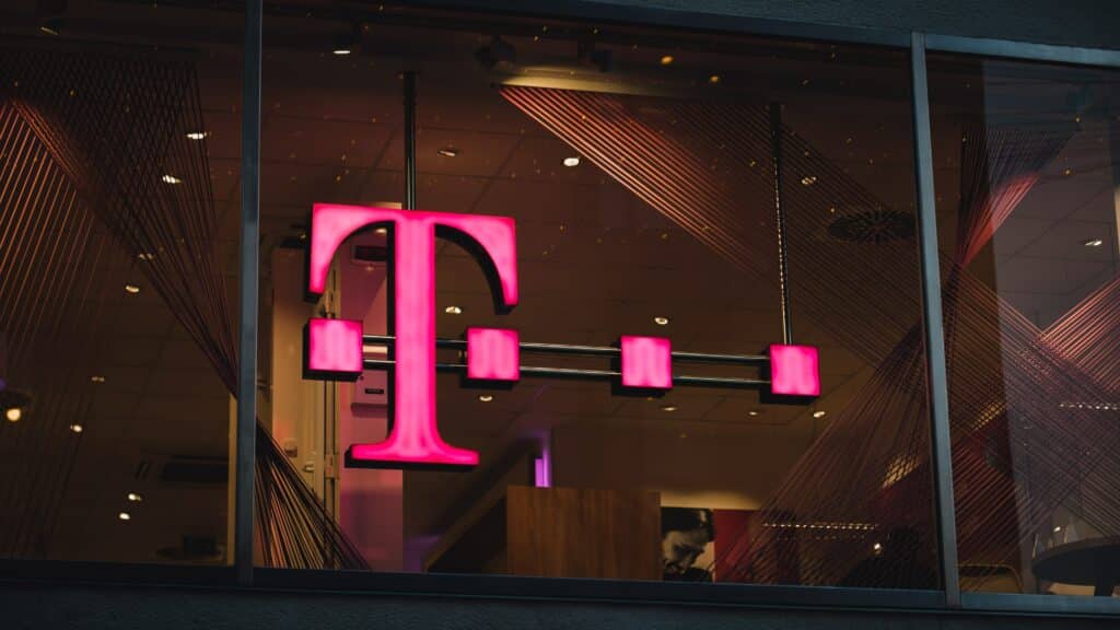 logo da T-Mobile pendurado numa loja, demonstrado pela letra T na cor rosa, com quatro pontos sobrepostos à letra.