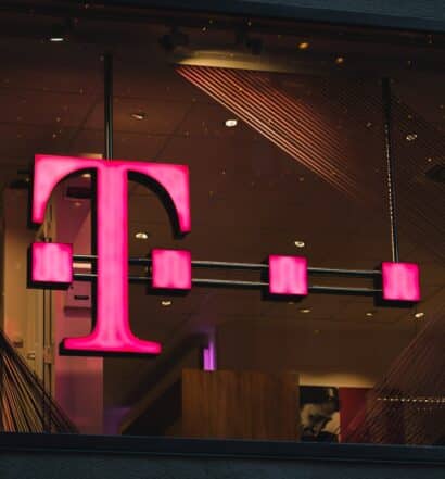 logo da T-Mobile pendurado numa loja, demonstrado pela letra T na cor rosa, com quatro pontos sobrepostos à letra.