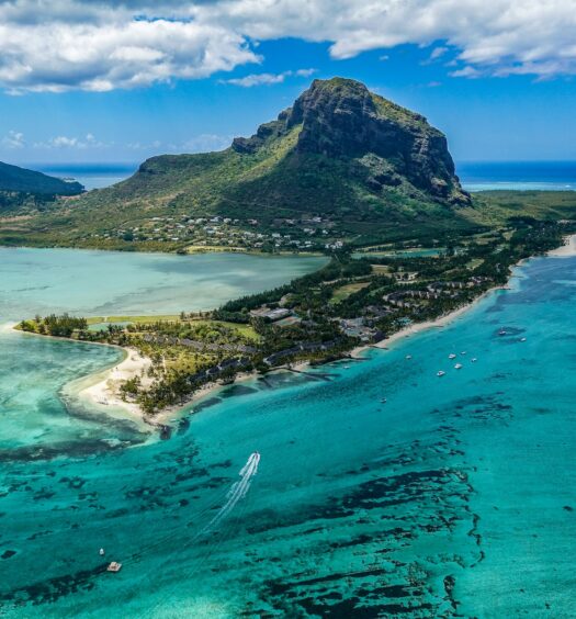 Fotografia aérea da ilha em tons de verde em volta do mar azul durante o dia, ilustrando post seguro viagem Ilhas Maurício.