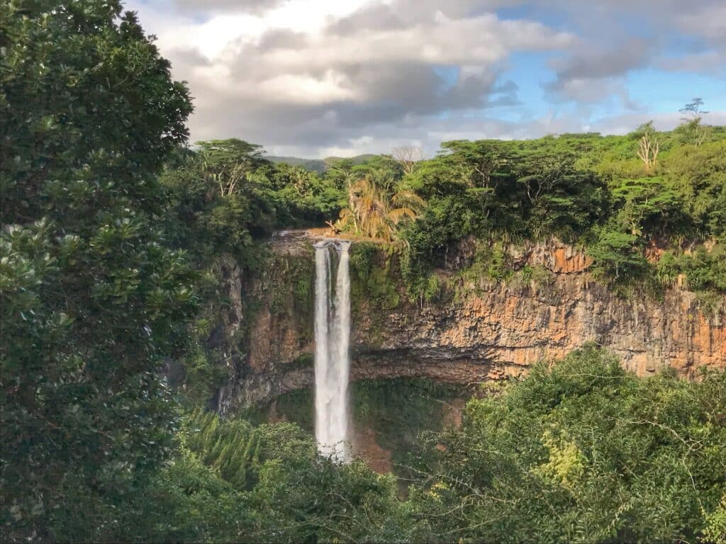 Cachoeira cercada por árvores em tons de verde durante o dia, ilustrando post seguro viagem Ilhas Maurício.