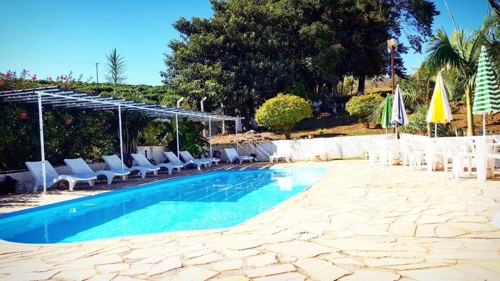 Vista da piscina do Chalé Alto da Serra SP durante o dia com cadeira em volta dela. Representa chalés em Serra Negra.