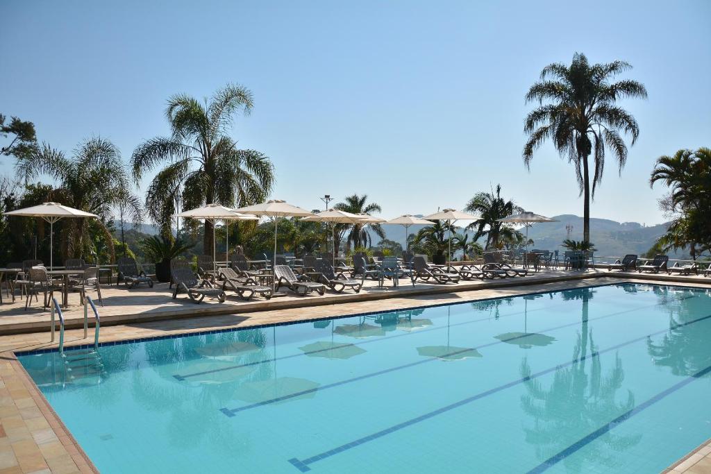 Vista da piscina do Grand Resort Serra Negra durante o dia com cadeiras e guarda-sóis no lado esquerdo.