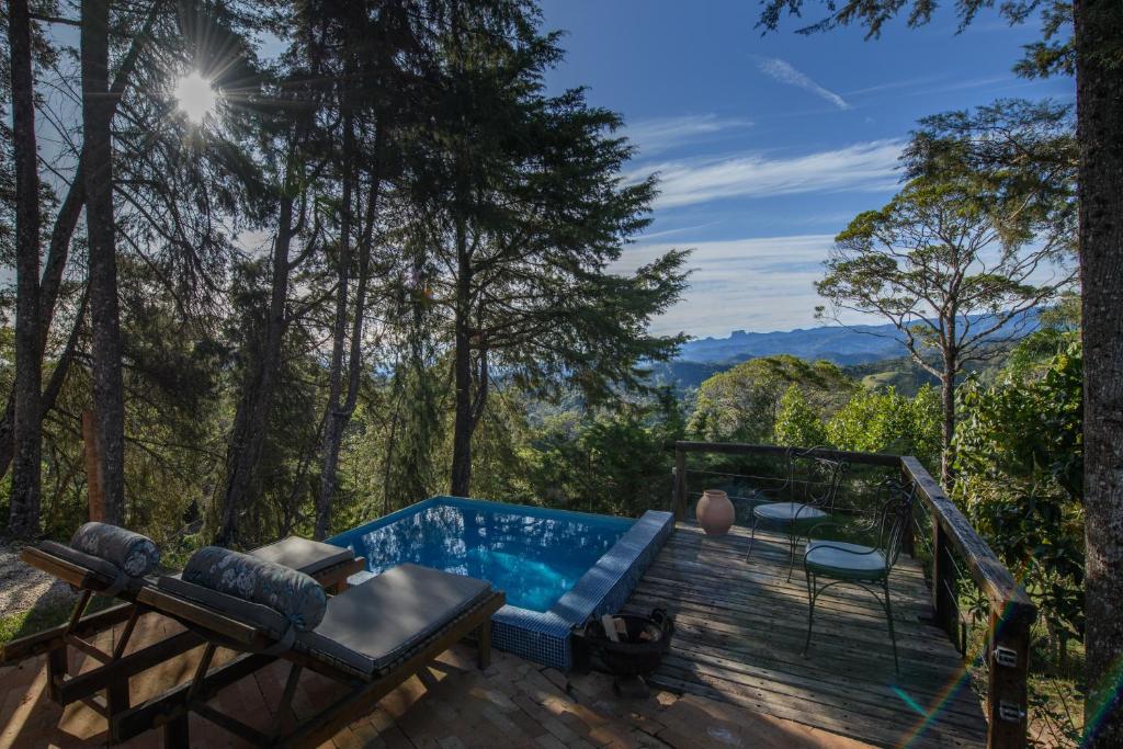 Vista da piscina do Quinta dos Pinhais Pouso e Charme com cadeira perto da piscina e com vista para árvores e montanhas.