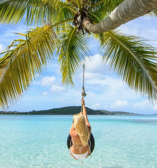 mulher em um balanço improvisado em um coqueiro que se projeta acima das águas cristalinas da Praia de Oppenheimer, em St. John, para ilustrar o post de chip celular Ilhas Virgens Americanas