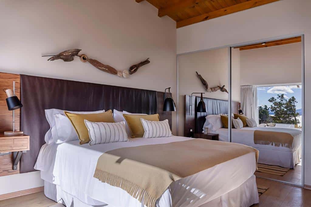 Quarto do Aguila Mora Suites & Spa com cama de casal, duas cômodas de madeira ao lado da cama e um guarda roupa com espelho do lado esquerdo da cama.