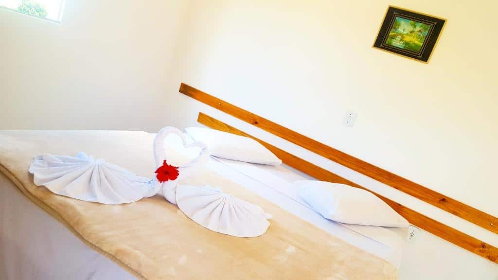 Quarto do Chalé Alto da Serra SP com cama de casal, dois travesseiros brancos na cama e duas toalhas brancas.