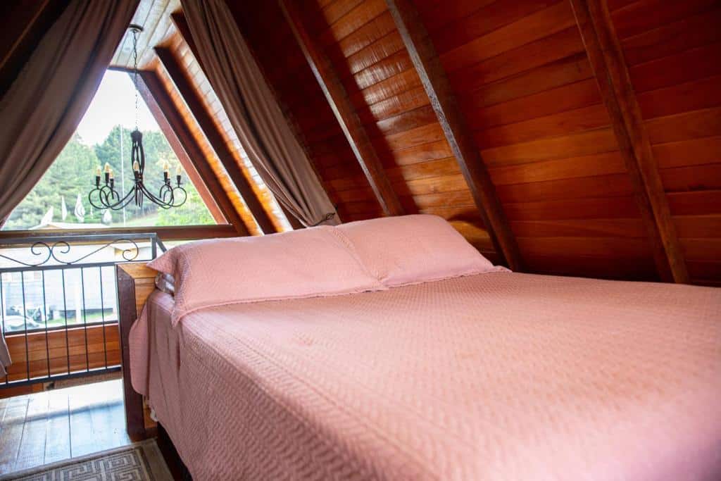 Quarto do Cabanas Floratta Wood, com cama de casal no lado direito e uma janela ampla de vidro do lado esquerdo.