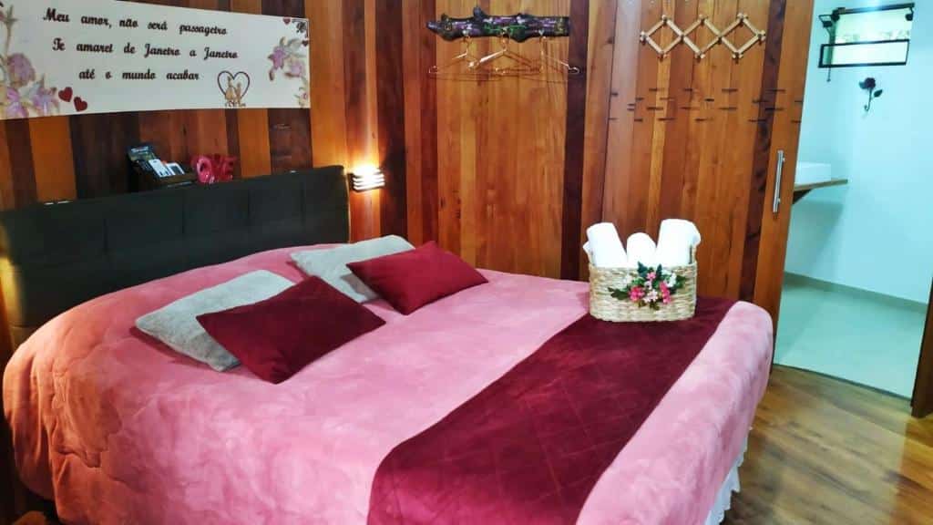 Quarto do Chalé Temático em Pipa de Vinho – Parada da Pipa Chalés com cama de casal, e um cesto de tolhas em cima da cama.