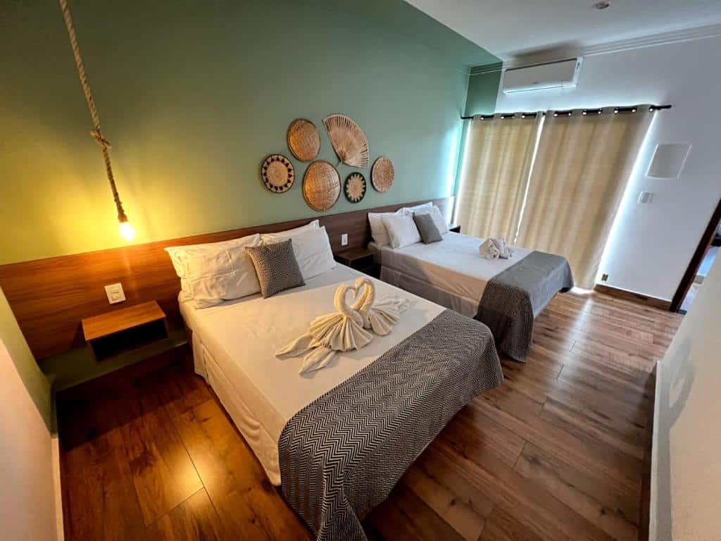 Quarto do Hotel Fazenda Vale da Cachoeira com duas camas de casal, com toalhas em cima da cama. Representa Chalés em Serra Negra.