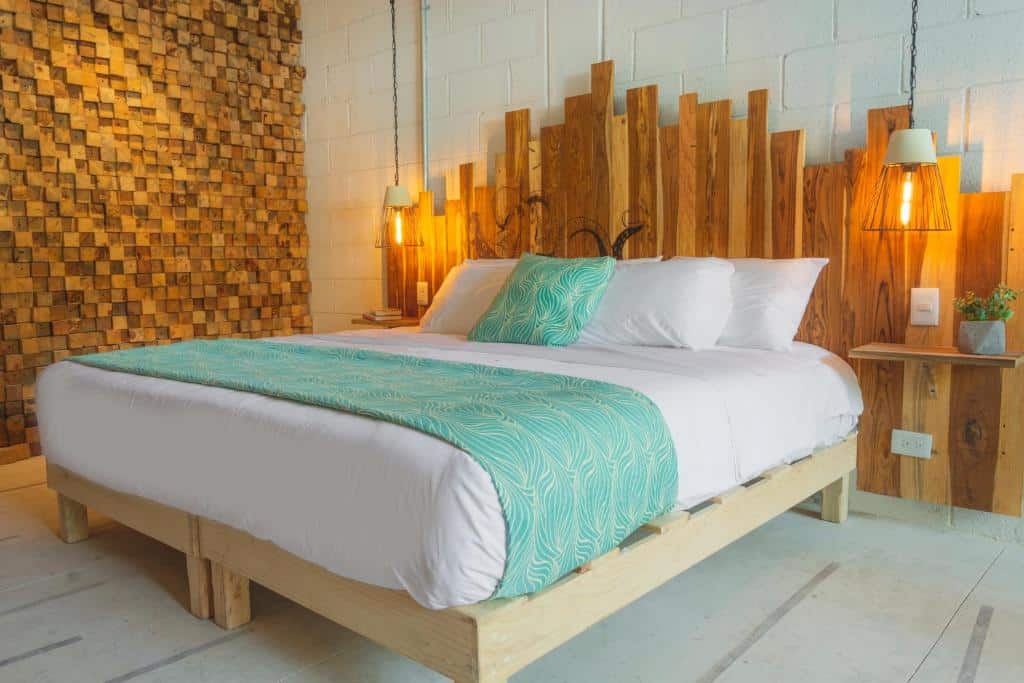 Quarto no Nomads Hotel & Beachclub com uma cama de casal, luminárias presas no teto e uma cabeceira de madeira rústica