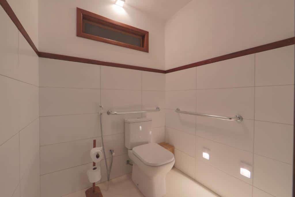 Banheiro com barras de apoio na lateral direita e acima do vaso sanitário de um bangalô da Pousada Samba Pa Ti