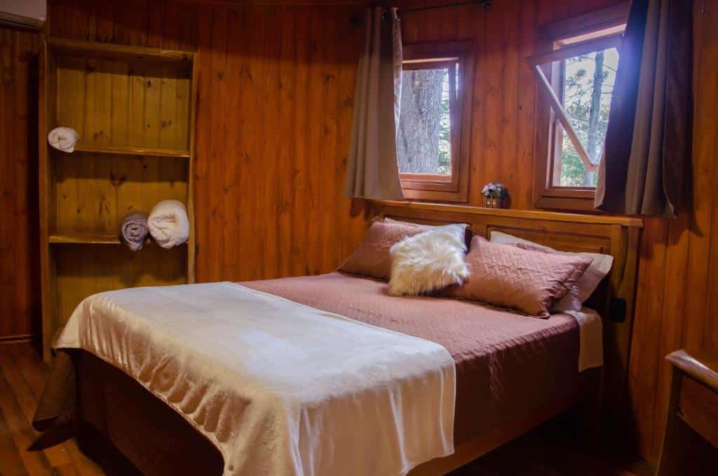 Quarto do Refúgio do Caracol Pipas e Chalés com cama de casal, cômoda de madeira do lado esquerdo.