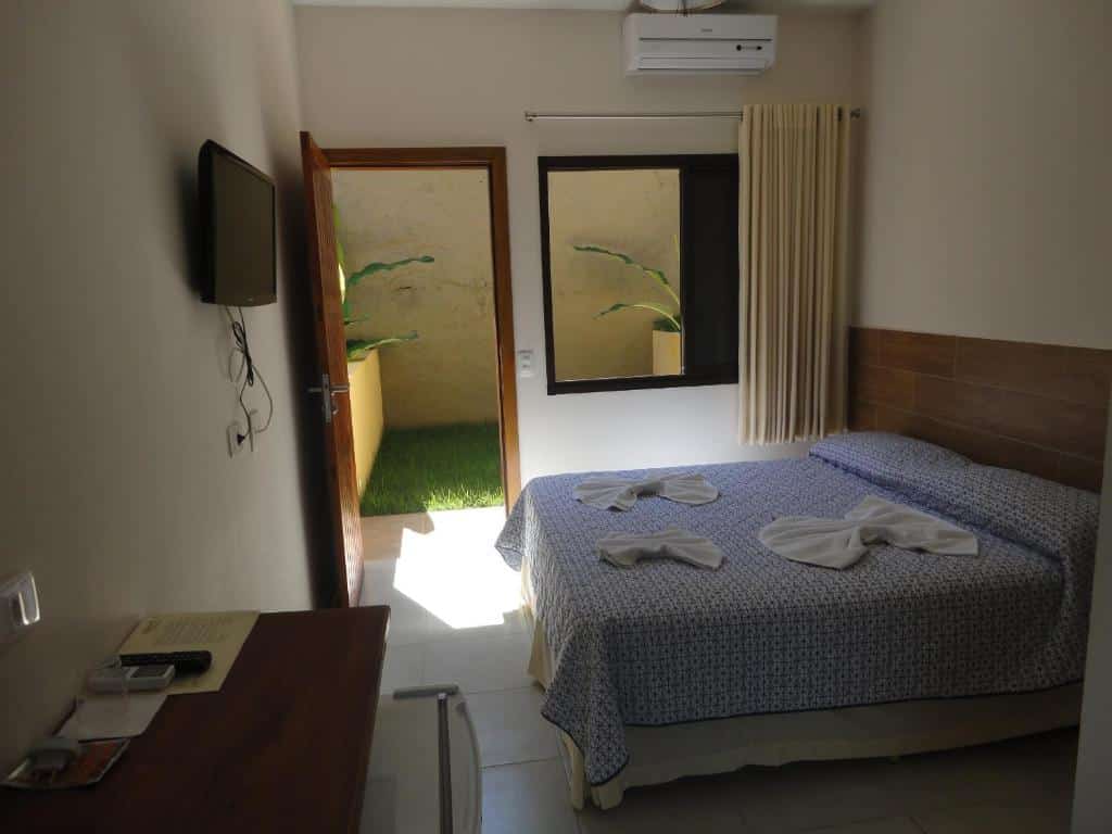 Quarto da Pousada Samburá com cama de casal, TV em frente a cama presa na parede e uma cômoda do lado direito.