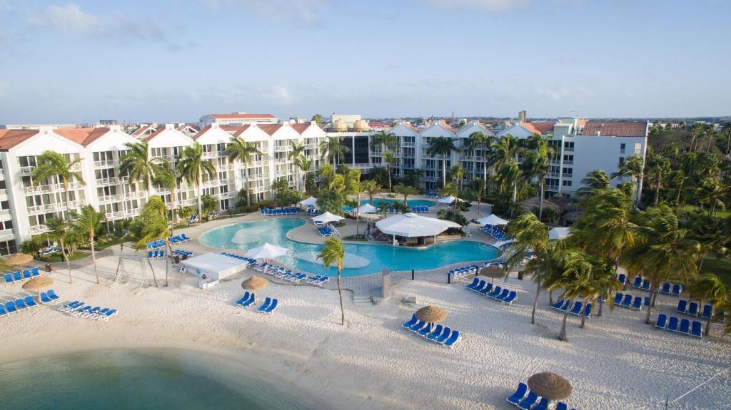 vista area do Renaissance Wind Creek Aruba Resort em frente ao mar, com espreguiçadeiras na areia e uma grande piscina entre os prédios