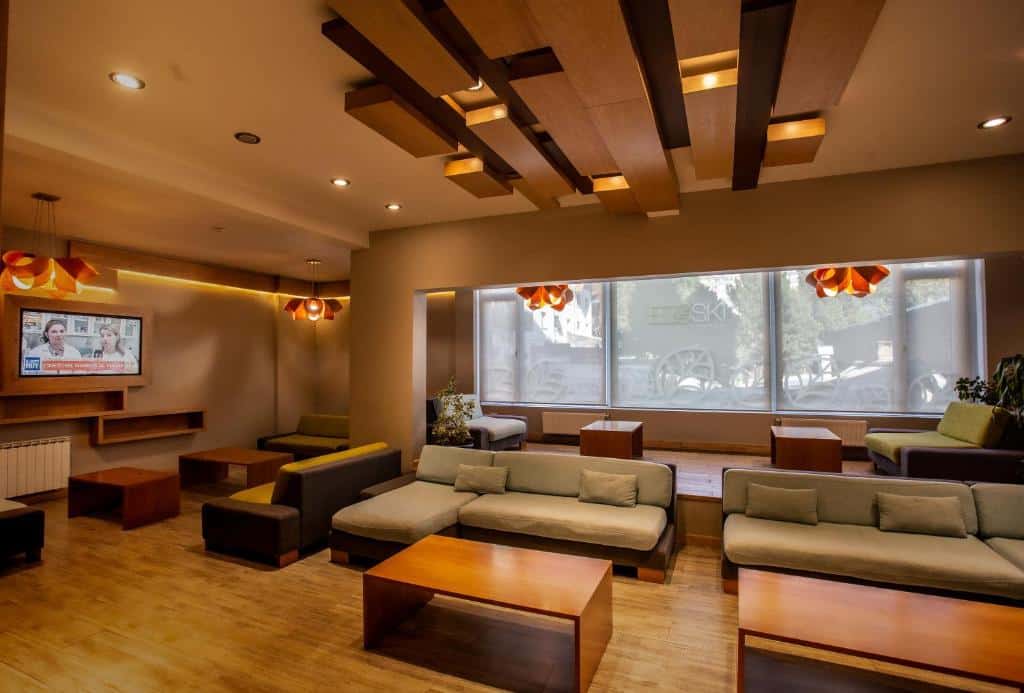 Sala de estar do Hotel EcoSki by bund com vários sofás, mesas e do lado esquerdo há uma TV. Representa hotéis em Bariloche.
