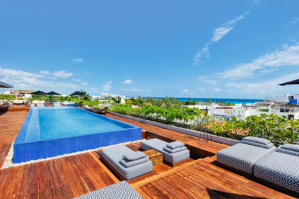 Piscina do The Yucatan Resort Playa del Carmen, All-Inclusive Adults Only, Tapestry by Hilton com um deck de madeira ao redor com várias espreguiçadeiras em formato de pequenos sofás