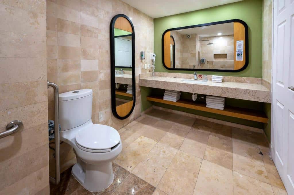Banheiro adaptado do Viva Wyndham Azteca All Inclusive com pia mais baixa e as prateleiras mais acessíveis com as toalhas e barras de apoio em todo o ambiente