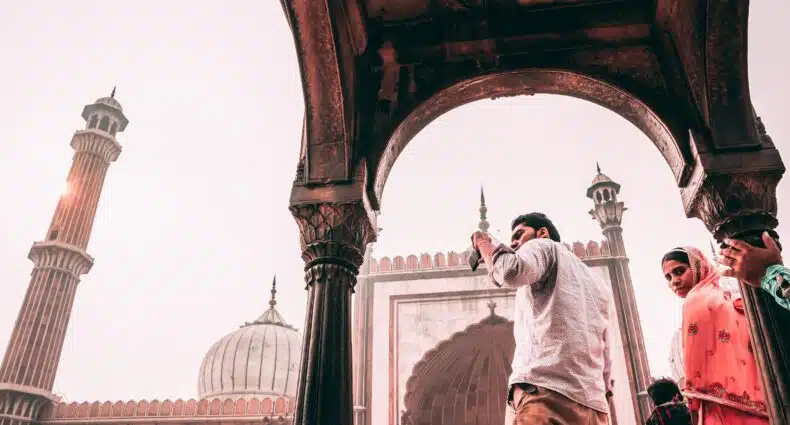 vista de baixo de algumas pessoas em Jama Masjid, em Nova Déli, um homem está tirando foto do templo que tem motivos indianos em tons de branco e amarronzado terra, para ilustrar o post de chip celular Índia