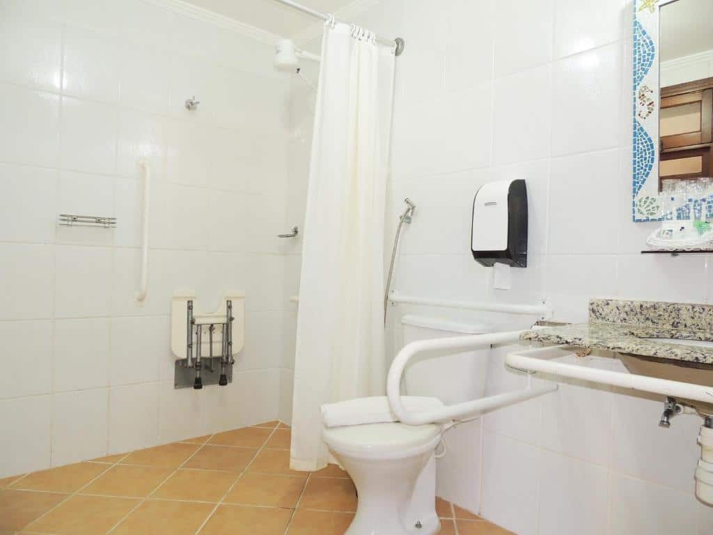 Banheiro adaptado da Pousada Mosaico Brasil – Maresias  com barras de apoio, pia mais baixa e box que não tem vidro apenas cortina