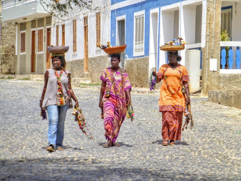 Foto de três mulheres negras, usando roupas coloridas típicas da África, e carregando cesto na cabeça. Imagem para ilustrar o post chip de celular Cabo Verde