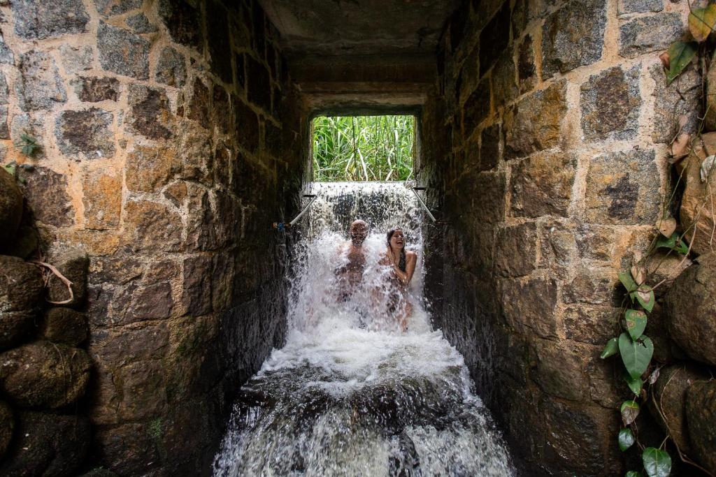 Uma queda d'água na Canto das Águas por entre paredes de pedra com duas pessoas se banhando