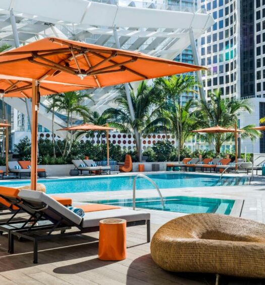 Vista da piscina East Miami, durante o dia com cadeiras em volta. Representa hotéis em Miami
