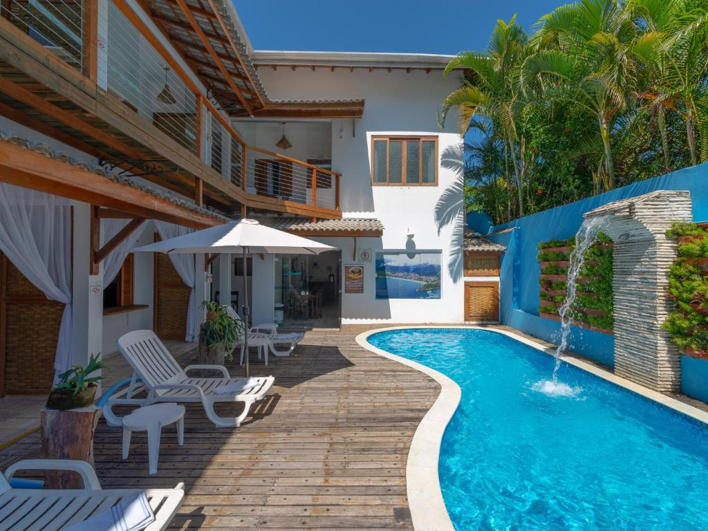 Vista da piscina da Pousada Vila Barequeçaba durante o dia com cadeiras brancas do lado esquerdo. Representa pousadas na praia de Guaecá.
